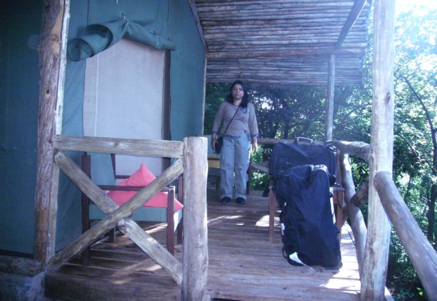 Chandrani in front of a cottage with a zipped door in Tanzania